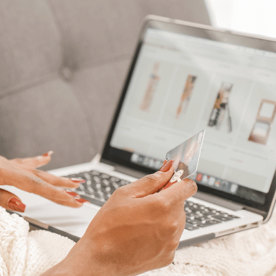 person sitting on a couch with laptop open, online shopping, holding credit card